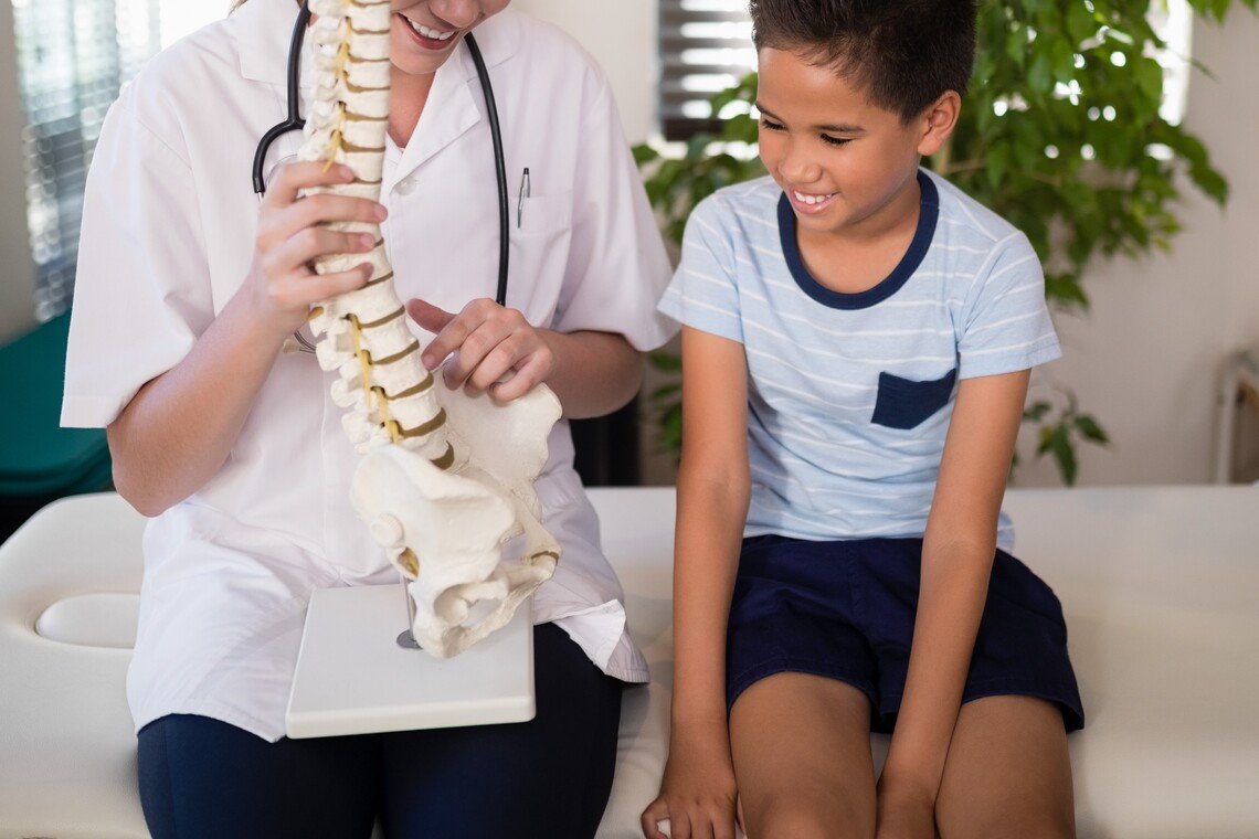 smiling-young-female-therapist-explaining-boy-with-2023-11-27-05-28-27-utc Smiling young female therapist explaining boy with artificial spine at hospital ward